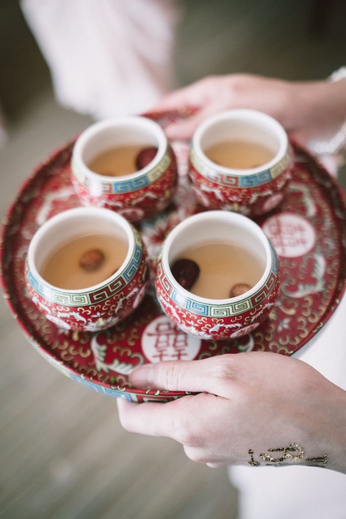 Unrecognizable female holding ceramic pot with cups of fresh aromatic tea in hands